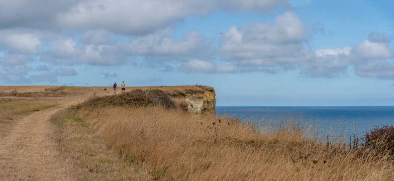 Arromanches-les-Bains, France - 08 10 2026:  Coastal path. Panoramic view of the cliffs and the sea and cloudy sky from top of the path