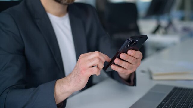 Cropped view male hands holding mobile phone unrecognizable Caucasian business man scrolling smartphone touchscreen technology in office unknown businessman worker at table with laptop hold cellphone