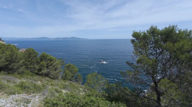 Scenic mediterranean sea view with pine trees and boat sailing