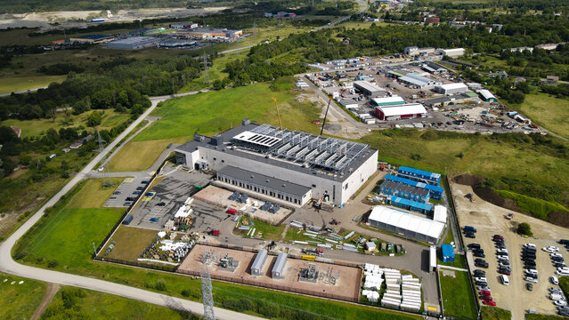 Aerial view showing a large data center building under construction with rooftop cooling systems. Adjacent power infrastructure. And temporary facilities