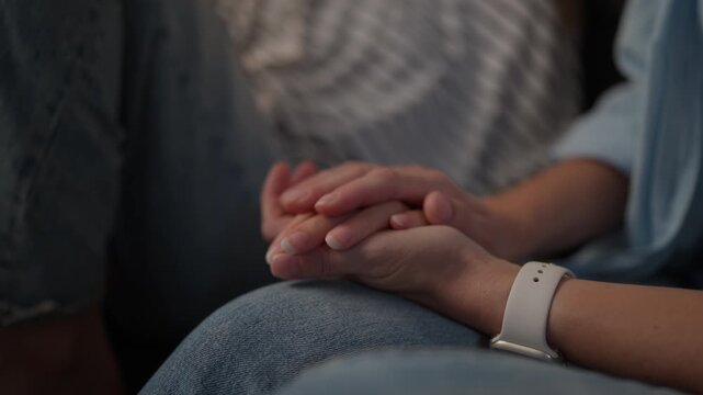 Close-up of mother gently holding and stroking her teenage daughter's hands, expressing emotional support, love, comfort, care and strong family connection.