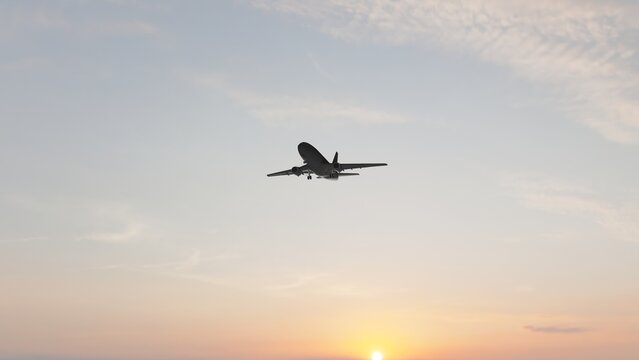  Commercial passenger airplane flying through a warm sunset sky, ideal for aviation, air travel, tourism, transportation, airline, and travel content.