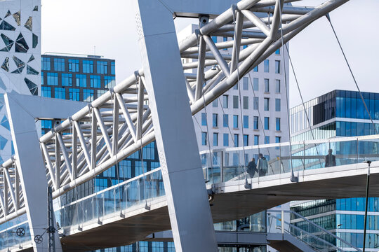 Pedestrian bridge and modern architecture in Oslo with steel structure crossing between glass buildings and geometric urban design in the city center