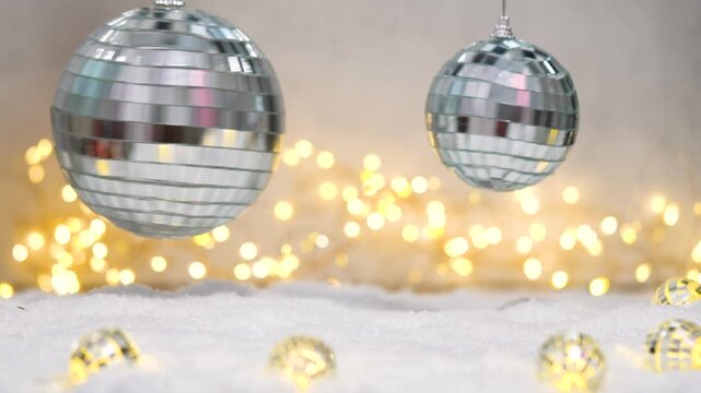 Sparkling disco mirror balls slowly rotate on soft snow, casting shifting reflections as warm fairy lights twinkle and flicker in the background, creating a festive party atmosphere.