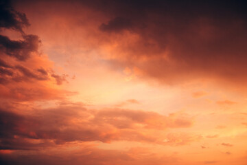 Fototapeta premium Spectacular fiery orange sky filled with towering storm clouds and dark atmospheric formations. Dramatic sunset, approaching storm, extreme weather concept.
