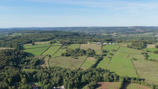 The rolling green fields, patchwork farmland, and scattered farmhouses of the Morvan region in France, aerial view.