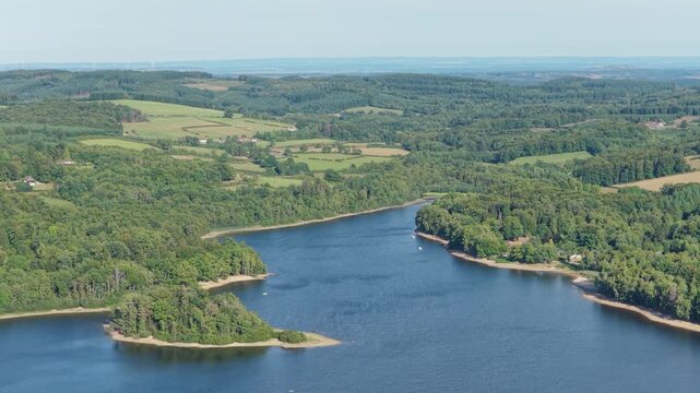 A high-resolution aerial video clip showcasing Lac des Settons in the Morvan region of France. The footage captures the expansive lake, lush green forests, and rolling countryside during a clear day.