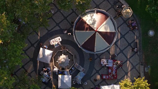 Aerial view of Jardim Visconde da Luz featuring a carousel, fountain, and market stalls on patterned pavement in Cascais, Lisboa, Portugal.