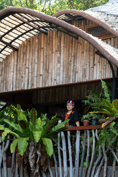 Malaysian indigenous Dayak woman in Bidayuh costume posing at the balcony of wooden and bamboo house