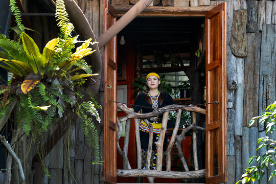 Malaysian indigenous Dayak woman standing at the window of wooden and bamboo house in a Lun Bawang traditional costume