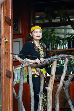 Malaysian indigenous Dayak woman standing at the window of wooden and bamboo house in a Lun Bawang traditional costume