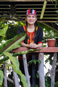 Malaysian indigenous Dayak woman in Bidayuh costume posing at the balcony of wooden and bamboo house