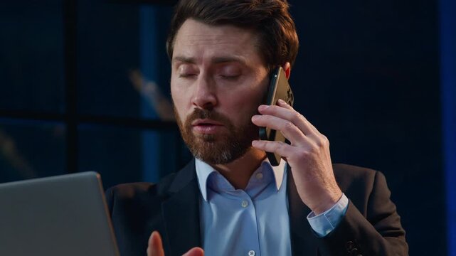 Close up Caucasian middle-aged business man working computer talking call at night evening office businessman male entrepreneur work online serious looking in monitor talk mobile phone conversation