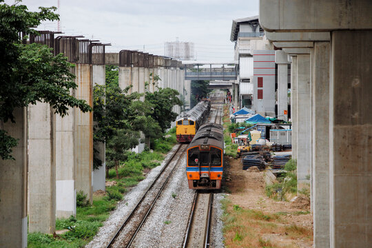 Trains Travel on Tracks Near Construction Site in Urban Area