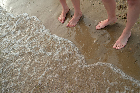 Legs of two women standing by the water
