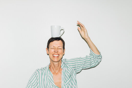 Woman Laughing With Coffee Mug on Head