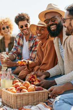 A group of diverse friends having an organic, aesthetic picnic in a sun-drenched public park.