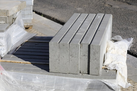 Grey curbstones are stored on the edge of a pavement that is being modernized