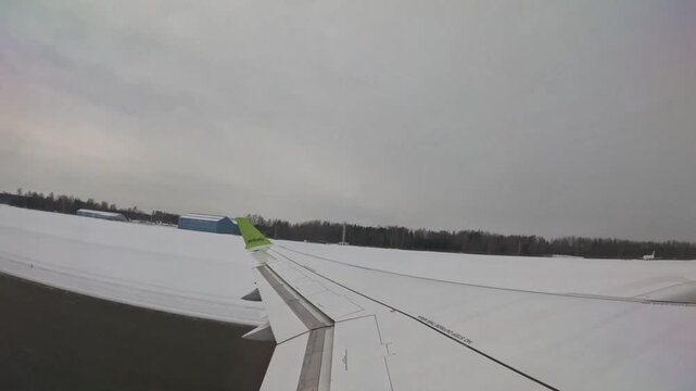 RIGA, LATVIA - FEBRUARY 10, 2024: AirBaltic airplane taking off and ascending over snowy winter landscape in Riga