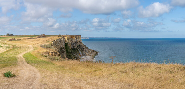 Arromanches-les-Bains, France - 08 10 2026: Coastal path. Panoramic view of the cliffs, the sea and cloudy sky from top of the path