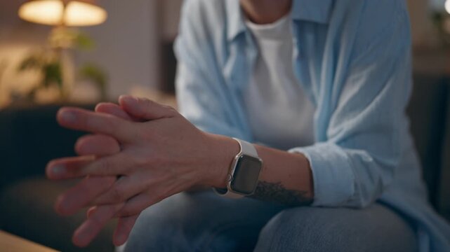 Close-up of woman hands rubbing together while sitting on sofa at home, illustrating nervousness, stress, anxiety, emotional tension and discomfort during a quiet moment.