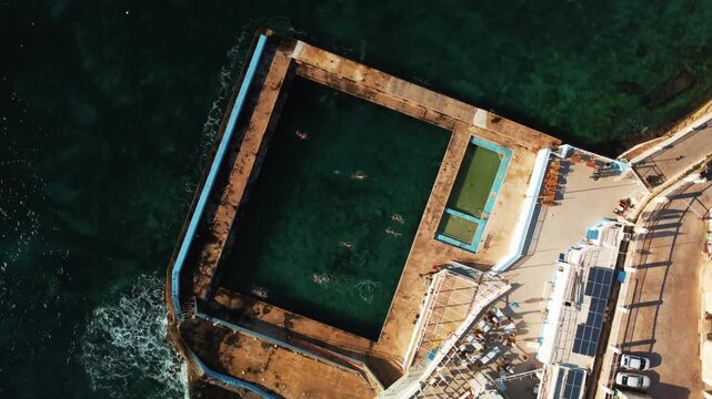 Swimmers Enjoy Coastal Tidal Pool. Drone Captures Lively Seaside Swim Area With Sunbathers