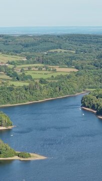 Lac des Settons in Morvan, France, showing the blue lake surrounded by lush green forests and rolling countryside, aerial vertical 9:16 view.