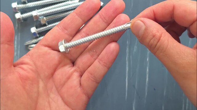 A person holding a self-drilling hex-head screw designed for use with a power drill