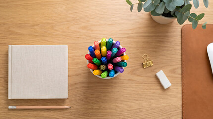 Naklejka premium Desk with colorful markers notebook and plant