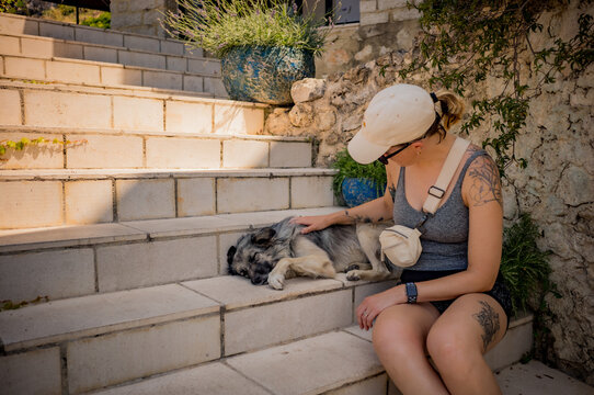 A woman petting a dog in the coastal village of Dh&euml;rmi in Albania.
