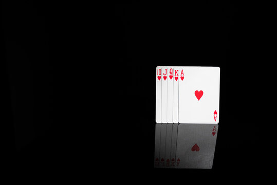 Royal flush of hearts playing cards on black background with mirror reflection. Concept of ultimate success, perfect hand, luck and winning.