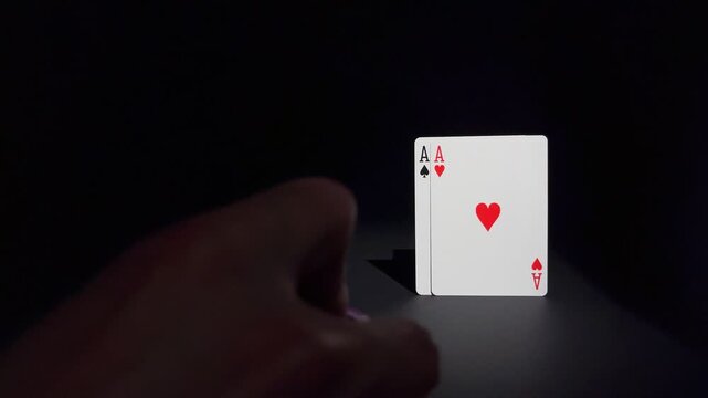 A hand pushes chips next to a pair of aces. Concept of luck, risk, gambling, strategy and winning hand.