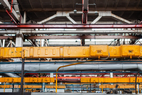 Close-up view of overhead industrial crane beam inside large manufacturing factory or industrial warehouse. Heavy industry, infrastructure, and mechanical engineering.