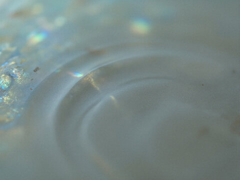Abstract macro view of iridescent nacre shell surface with circular ripples and soft highlights