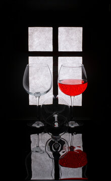 Still life with glasses and red wine against the background of a window silhouette