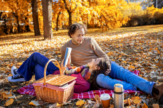 Family relaxing with books and picnic basket outdoors