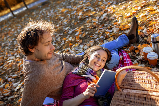 Young couple smiling together on autumn picnic blanket