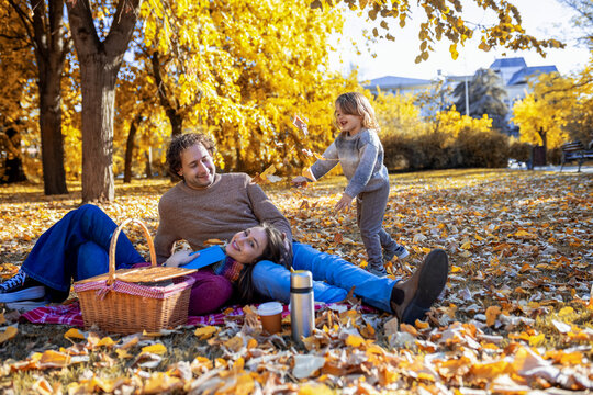 Father sitting with son on grass in autumn park