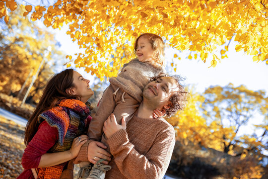 Low angle view of parents carrying son in autumn