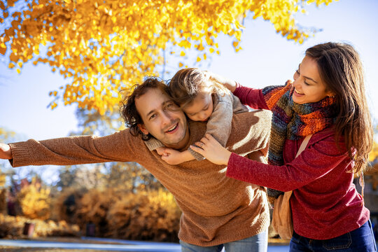 Father giving son a piggyback ride in autumn park