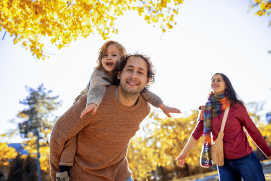 Family walking and playing with piggyback ride in fall