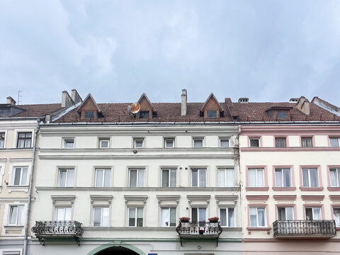 European old town buildings with ornate balconies against cloudy sky, architectural facade detail