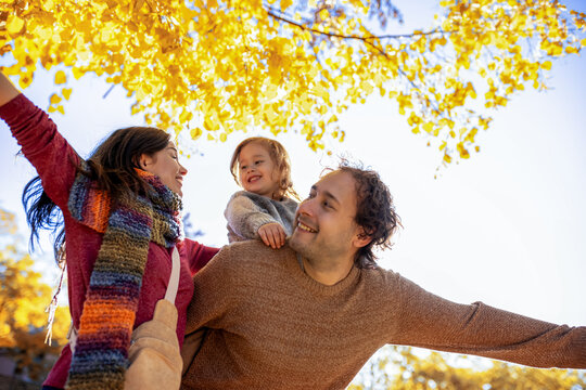 Happy parents holding son under autumn canopy