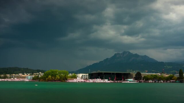 Dramatic stormy timelapse of Mount Pilatus and Lucerne lakefront with rushing clouds over KKL culture center and Lake Lucerne in Switzerland