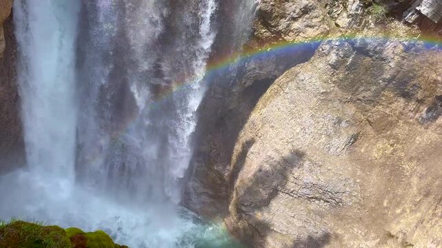 Johnston Creek river in Johnston Canyon in the Banff National Park. British Columbia, Canada. Water flows powerfully over a rocky cliff, creating a rainbow in the mist above the waterfall