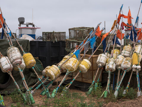 Marker buoys with orange flags and octopus traps stored at a fishing harbour, Portugal