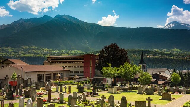 Brig Switzerland cemetery timelapse with rushing clouds over alpine mountain peak landscape in sunny summer valley