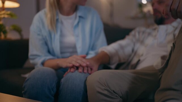 Woman comforting upset partner while sitting together on sofa at home, gently stroking arm and offering emotional support, empathy, care and reassurance during a difficult moment.