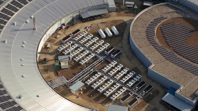 Aerial view of the Harwell Oxford research facility showing the circular building, solar panels, and industrial cooling units in Harwell Oxford, England, United Kingdom.