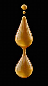 Golden droplet hangs suspended in pure darkness. Surface gleams with subtle shimmering light.